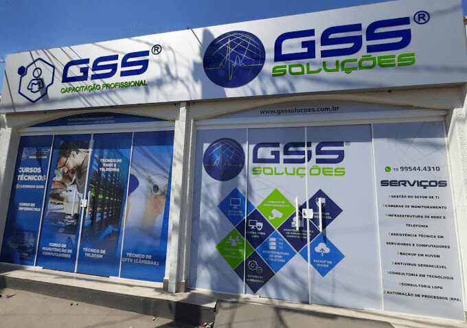 Fachada de uma loja da GSS Soluções, exibindo banners de cursos e serviços oferecidos pela empresa. A fachada azul e branca apresenta logos e informações de contato.